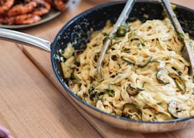 Delicious tagliatelle pasta with creamy zucchini sauce in a pan, perfect for a gourmet meal.