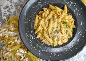 Delicious creamy penne pasta garnished with cheese and parsley.