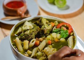 A vibrant bowl of vegetable and pasta soup, garnished with fresh herbs, perfect for a hearty meal.
