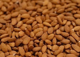 A detailed close-up of a large batch of raw almonds, emphasizing texture and natural detail.